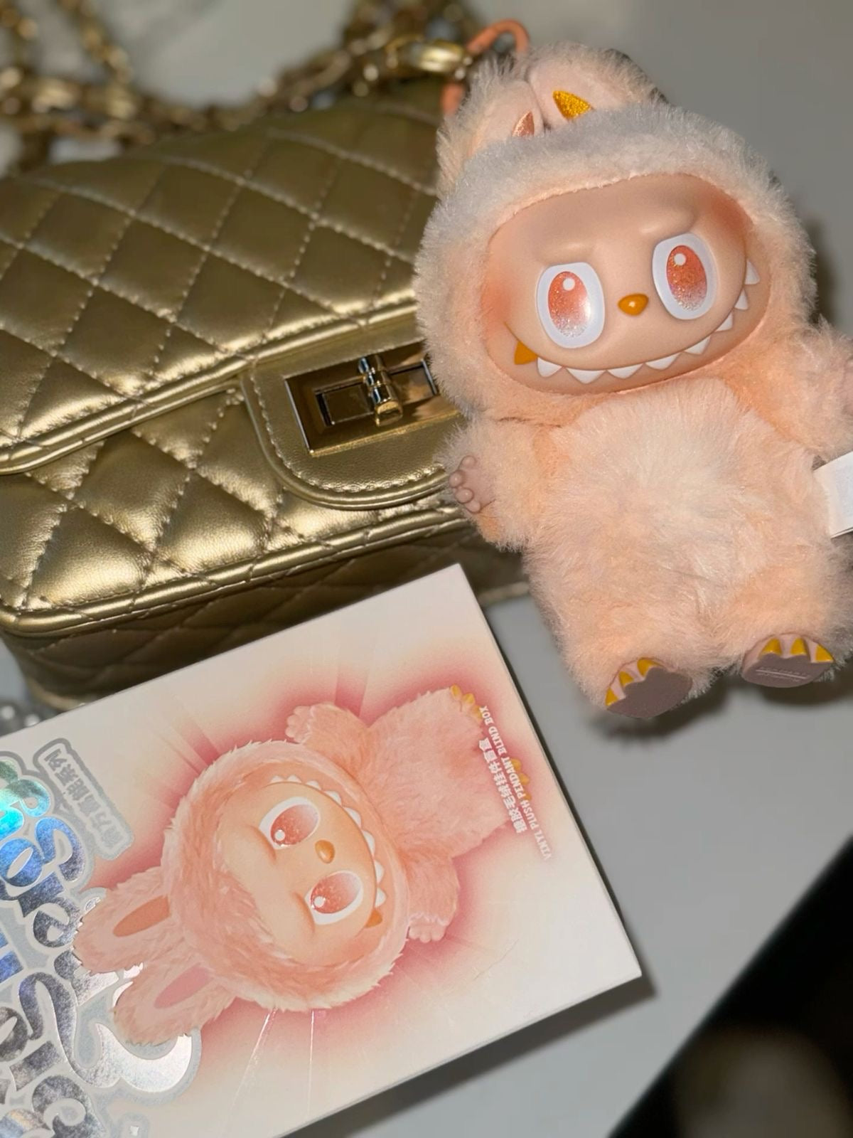 Plush toy with a gold handbag and card in the background