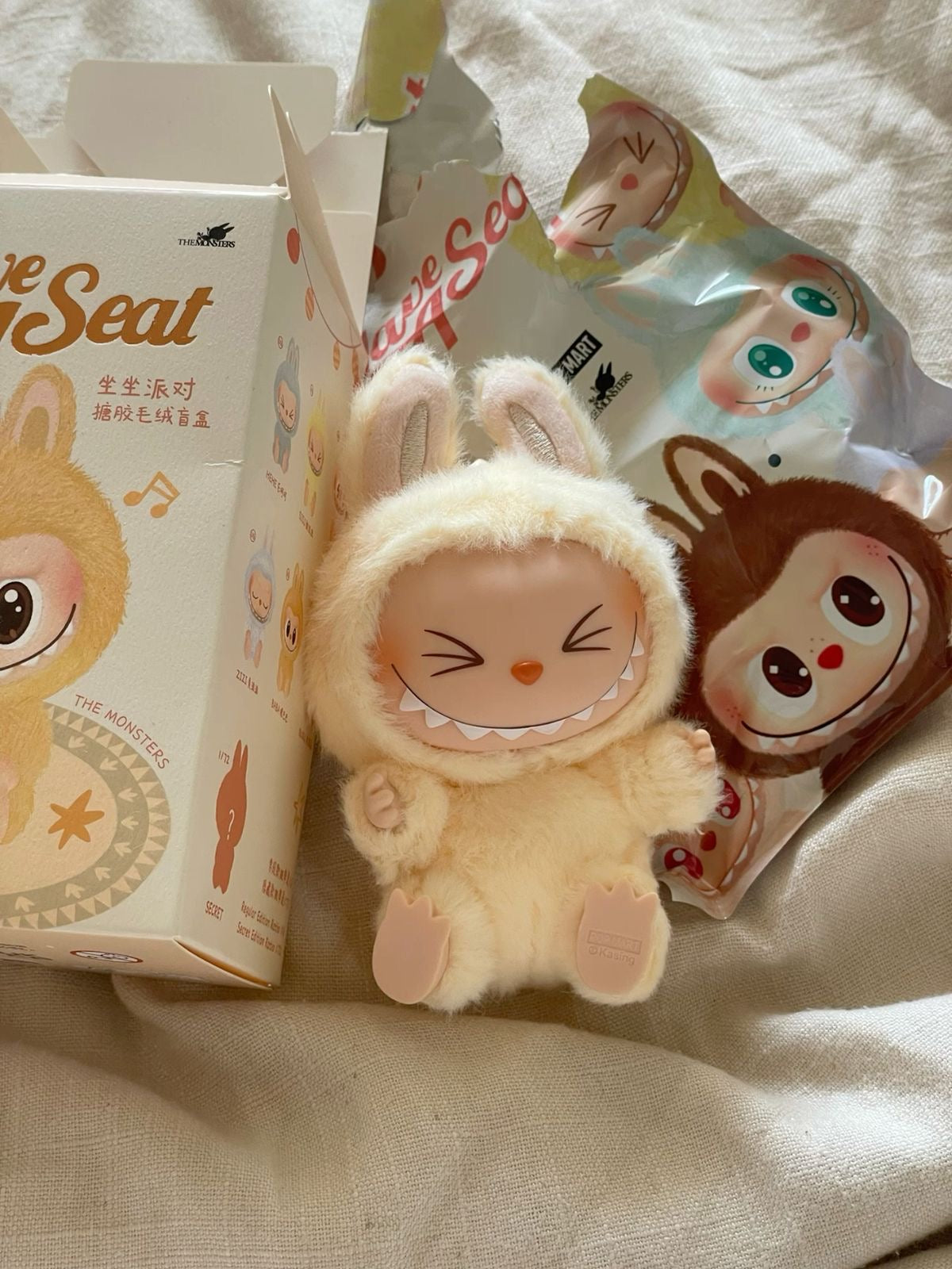 Plush toy resembling a character with a box and packaging in the background