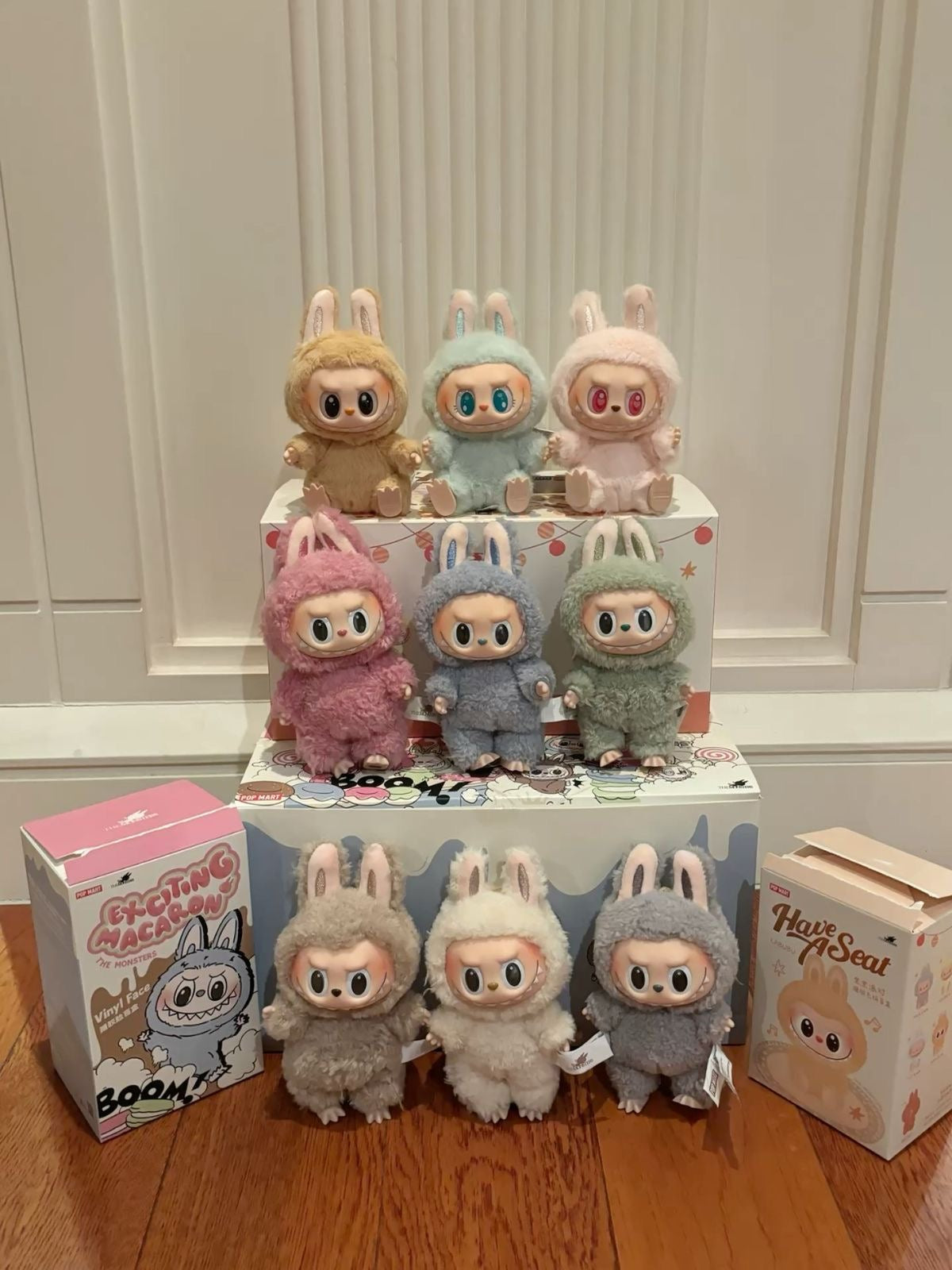 Collection of plush toys in various colors on a display stand with boxes in the foreground.
