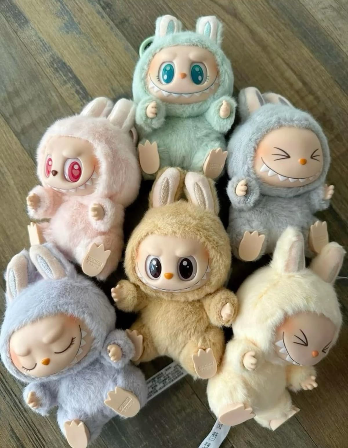 Set of colorful plush toys with rabbit-like designs on a wooden surface