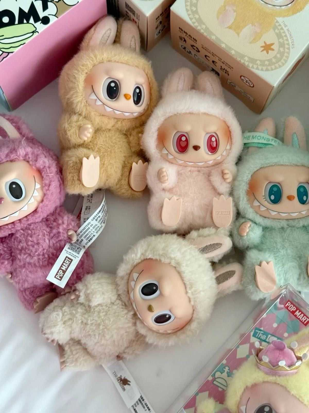 Collection of colorful plush toys with tags on a white surface