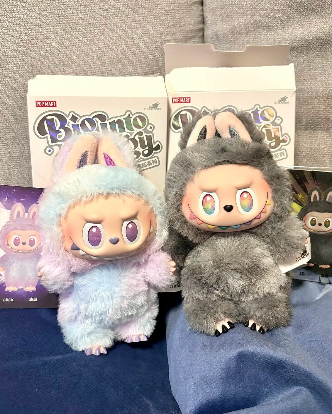 Two plush toys with boxes labeled 'BiG into ENERGY' on a gray surface.