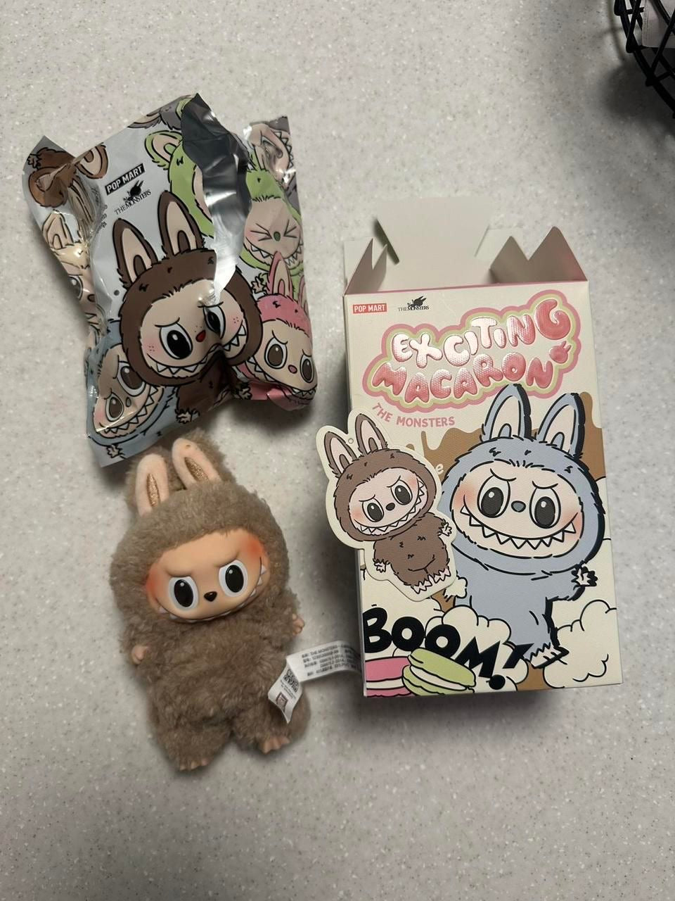 Plush toy and packaging with cartoon characters on a gray surface